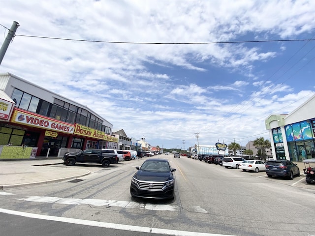 view of asphalt road featuring curbs, sidewalks, and street lighting