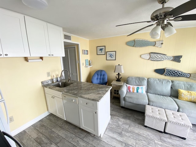kitchen featuring a sink, dishwasher, a peninsula, white cabinets, and wood finish floors