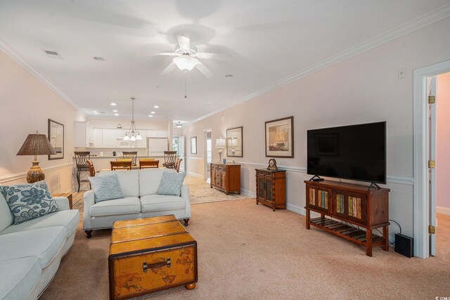 living area with light carpet, ornamental molding, a ceiling fan, recessed lighting, and a chandelier