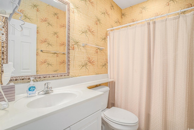 bathroom with wallpapered walls, vanity, and toilet