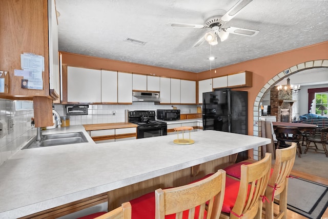 719 Juniper Dr, Myrtle Beach, SC 29575 - kitchen featuring black appliances, a sink, a peninsula, under cabinet range hood, and light countertops