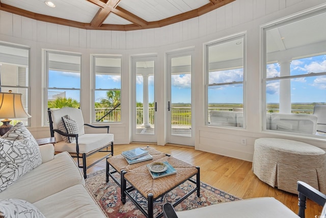 sunroom with healthy amount of natural light, beam ceiling, coffered ceiling, wood finished floors, and a wooden deck