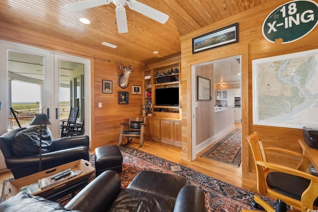 living area featuring wood walls, wooden ceiling, light wood-style floors, a ceiling fan, and built in features