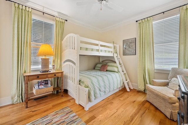 bedroom featuring ornamental molding, baseboards, wood finished floors, and a ceiling fan