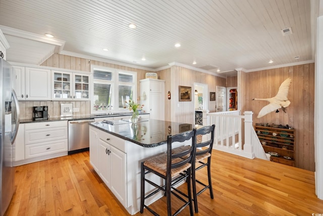 kitchen with appliances with stainless steel finishes, a kitchen breakfast bar, crown molding, white cabinets, and light wood-style floors