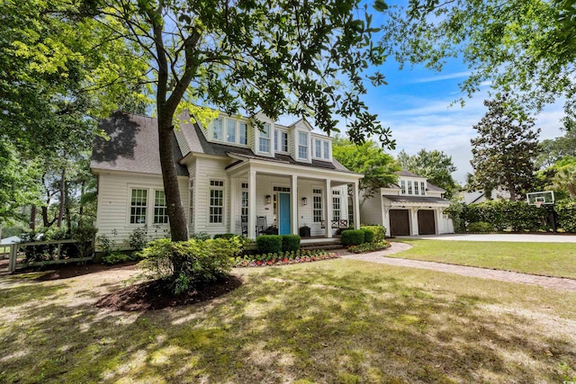 view of front of home featuring covered porch, a garage, a front lawn, and driveway