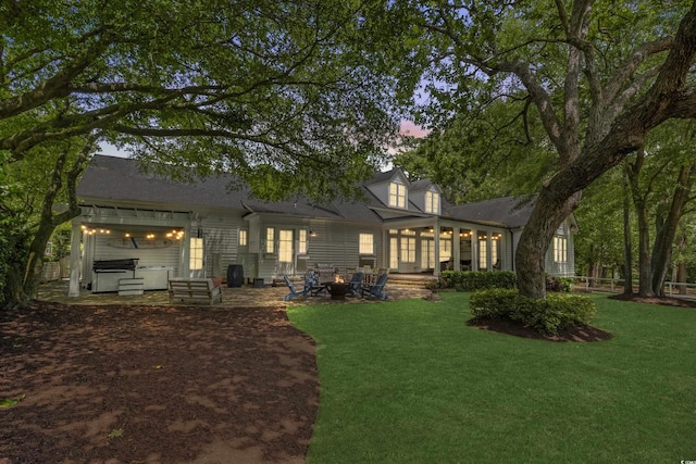 back of house with a hot tub, a yard, a patio, and an outdoor fire pit