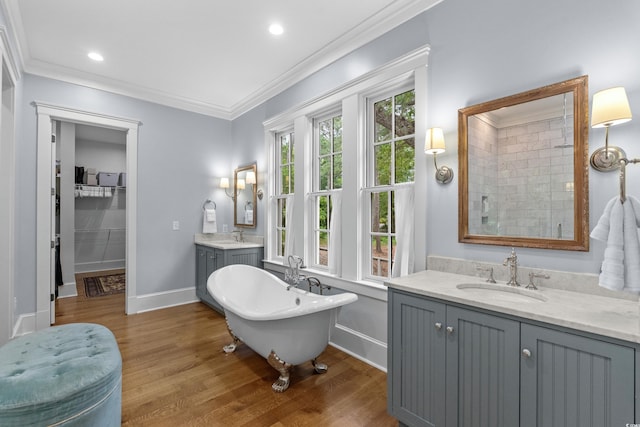 bathroom with wood finished floors, baseboards, crown molding, tiled shower, and a freestanding bath