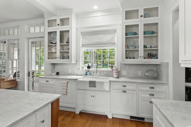 kitchen featuring a sink, backsplash, white cabinets, crown molding, and beamed ceiling