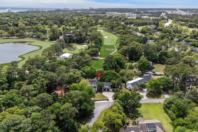 aerial view of property's location with a nearby body of water, a local golf course, and a tree filled landscape
