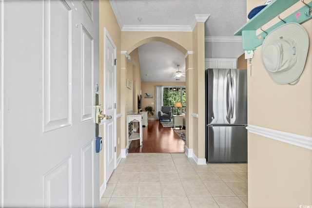 entrance foyer featuring light tile patterned flooring, arched walkways, ornamental molding, a ceiling fan, and baseboards