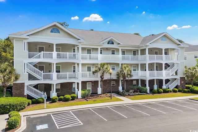 view of property with stairway and uncovered parking