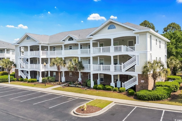 view of property with stairs and uncovered parking