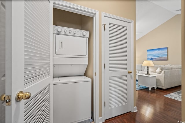 laundry room with estacked washer and dryer, dark wood-style flooring, and baseboards