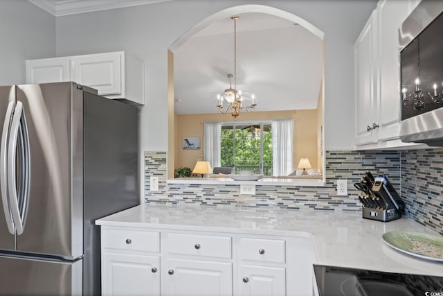 kitchen with freestanding refrigerator, a chandelier, light countertops, backsplash, and white cabinetry