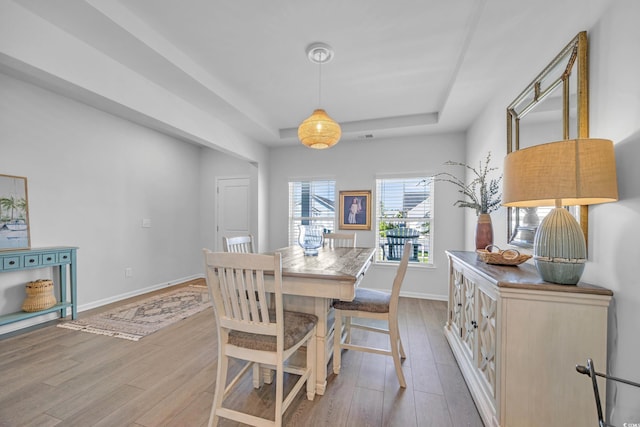 dining room featuring hardwood / wood-style floors, baseboards, and a raised ceiling