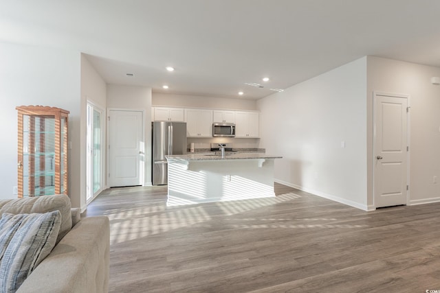 kitchen with stainless steel appliances, open floor plan, baseboards, light wood-style floors, and white cabinets
