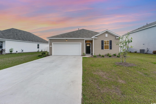 ranch-style home featuring cooling unit, an attached garage, concrete driveway, and a front lawn