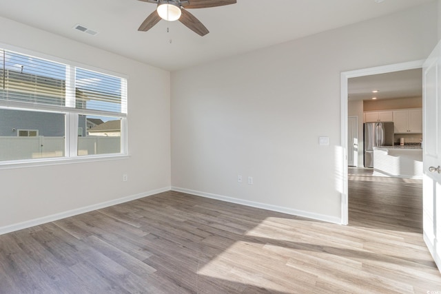 empty room with a ceiling fan, light wood-type flooring, and baseboards