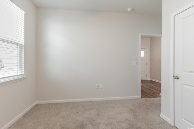 carpeted spare room with baseboards and a smoke detector