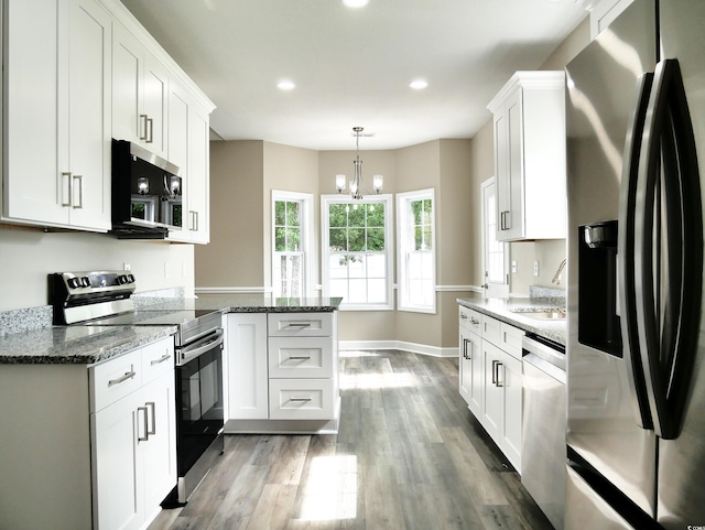104 Jessica Lakes Dr, Conway, SC 29526 - kitchen featuring appliances with stainless steel finishes, a peninsula, wood finished floors, white cabinets, and dark stone countertops