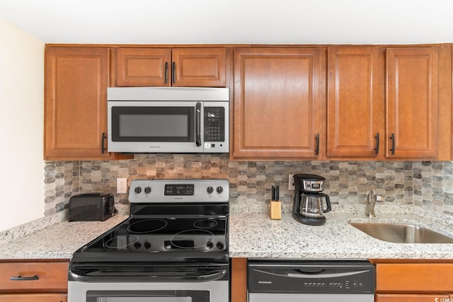 7509 N Ocean Blvd Unit 404, Myrtle Beach, SC 29572 - kitchen featuring stainless steel appliances, a sink, backsplash, light stone counters, and brown cabinets