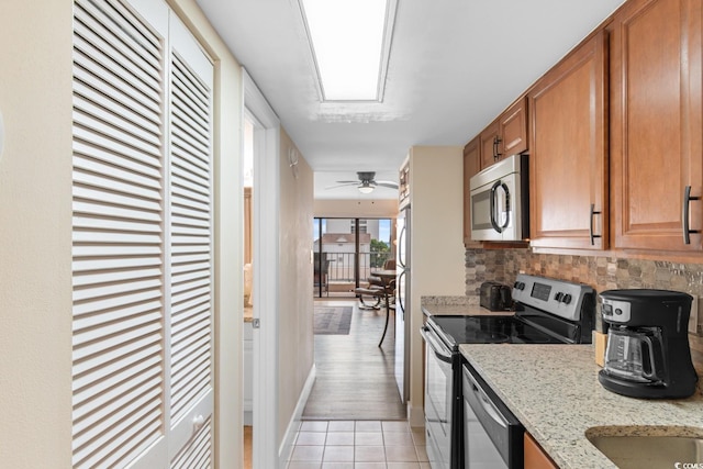 7509 N Ocean Blvd Unit 404, Myrtle Beach, SC 29572 - kitchen featuring appliances with stainless steel finishes, decorative backsplash, brown cabinetry, light tile patterned floors, and light stone counters