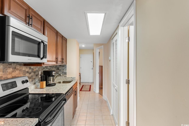 7509 N Ocean Blvd Unit 404, Myrtle Beach, SC 29572 - kitchen with stainless steel appliances, a sink, brown cabinetry, tasteful backsplash, and light tile patterned floors