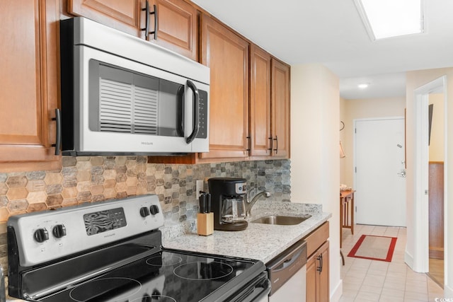 7509 N Ocean Blvd Unit 404, Myrtle Beach, SC 29572 - kitchen with stainless steel appliances, a sink, tasteful backsplash, light stone countertops, and brown cabinetry