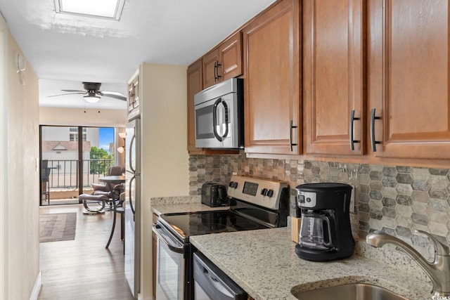 7509 N Ocean Blvd Unit 404, Myrtle Beach, SC 29572 - kitchen featuring stainless steel appliances, a sink, brown cabinets, light stone countertops, and wood finished floors