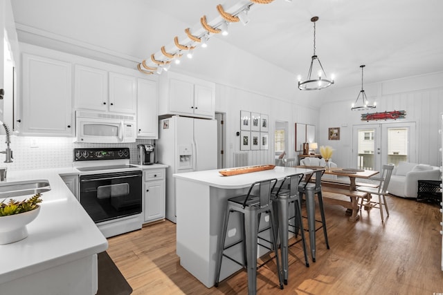337 59th Ave N, North Myrtle Beach, SC 29582 - kitchen with white appliances, a sink, a kitchen breakfast bar, light wood finished floors, and white cabinetry