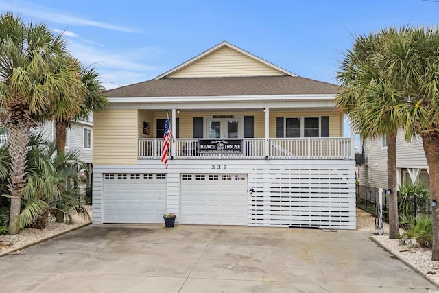 337 59th Ave N, North Myrtle Beach, SC 29582 - raised beach house featuring concrete driveway, roof with shingles, an attached garage, and a porch