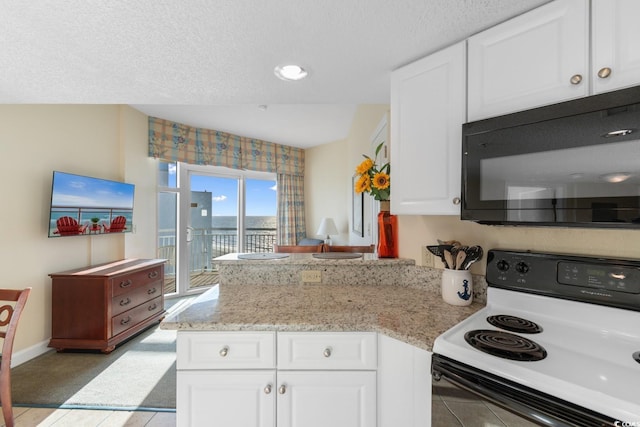 2501 S Ocean Blvd Unit 831, Myrtle Beach, SC 29577 - kitchen featuring black microwave, range with electric cooktop, a peninsula, white cabinetry, and light tile patterned flooring