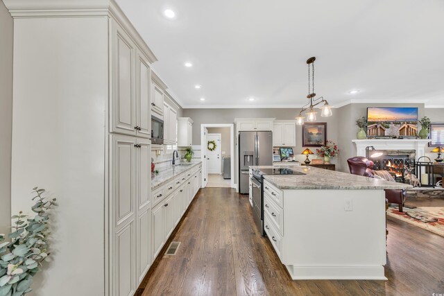 kitchen with a sink, stainless steel appliances, a lit fireplace, crown molding, and light stone countertops
