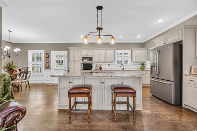 kitchen featuring appliances with stainless steel finishes, a chandelier, a breakfast bar area, hanging light fixtures, and ornamental molding