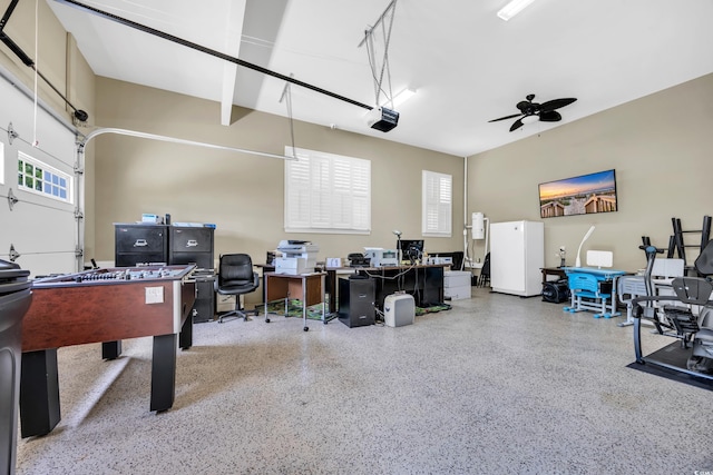 recreation room featuring speckle patterned floor, an office area, a ceiling fan, and a garage