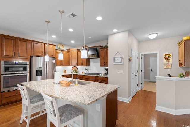 1035 Brentford Pl, Myrtle Beach, SC 29579 - kitchen featuring stainless steel appliances, a sink, premium range hood, brown cabinets, and a kitchen bar