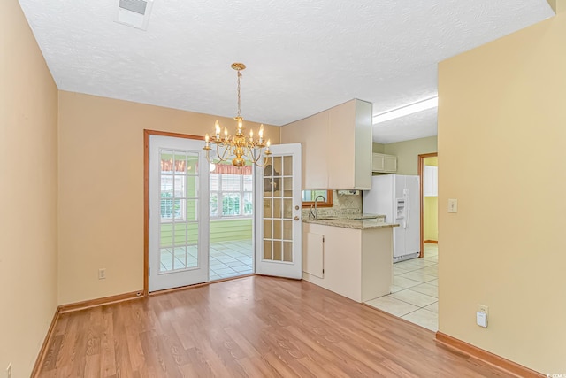 934 Tiffany Ln, North Myrtle Beach, SC 29582 - kitchen with white fridge with ice dispenser, a chandelier, light wood-style floors, a sink, and tasteful backsplash