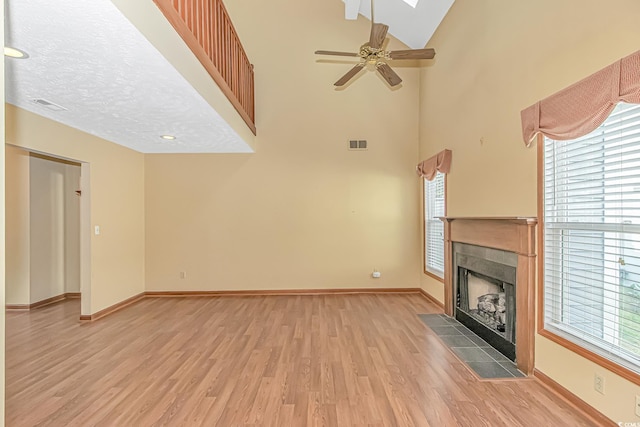 934 Tiffany Ln, North Myrtle Beach, SC 29582 - unfurnished living room with light wood-style floors, a tiled fireplace, baseboards, high vaulted ceiling, and ceiling fan