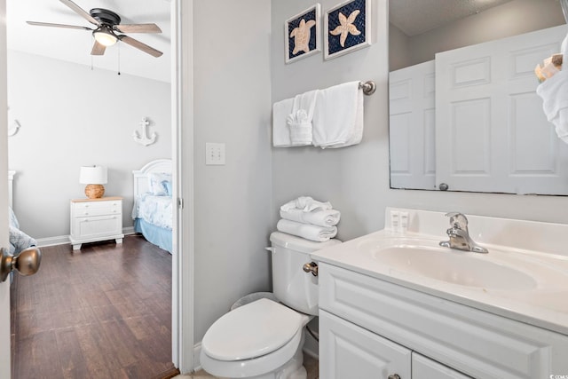 ensuite bathroom with a ceiling fan, toilet, wood finished floors, and vanity