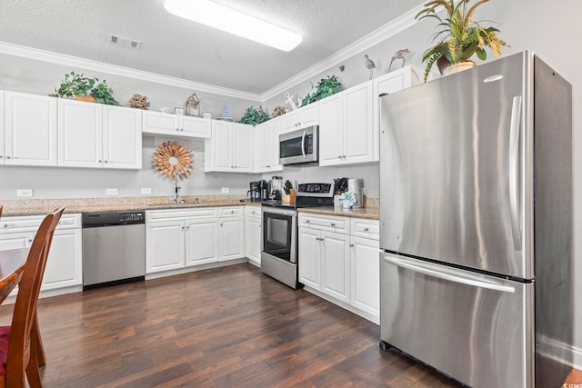 kitchen featuring appliances with stainless steel finishes, a textured ceiling, dark wood finished floors, white cabinetry, and crown molding