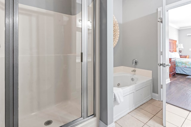 ensuite bathroom with a stall shower, a jetted tub, tile patterned floors, ornamental molding, and baseboards