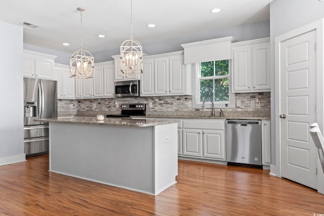 kitchen with stainless steel appliances, a chandelier, a sink, wood finished floors, and recessed lighting