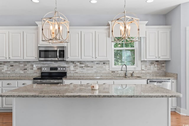 kitchen featuring a chandelier, stainless steel appliances, a sink, white cabinetry, and recessed lighting