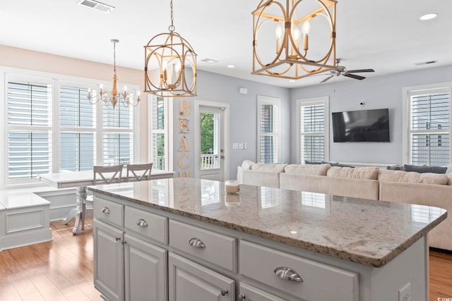 kitchen with a chandelier, light wood finished floors, a ceiling fan, a center island, and recessed lighting
