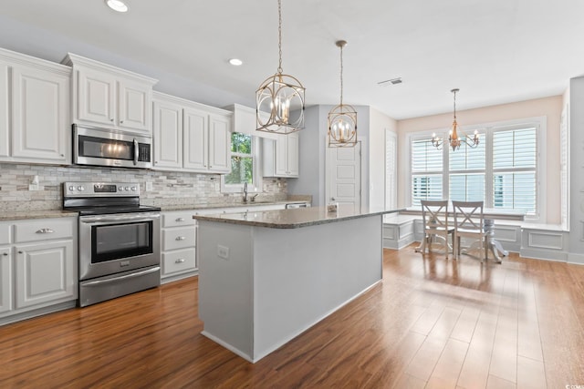 kitchen with appliances with stainless steel finishes, a chandelier, dark wood finished floors, plenty of natural light, and recessed lighting