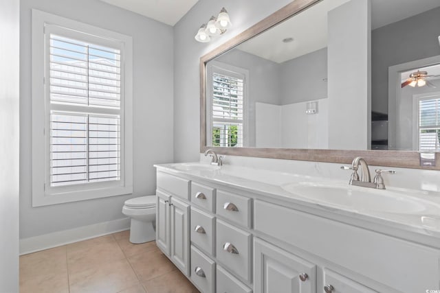 bathroom with baseboards, tile patterned flooring, toilet, double vanity, and ceiling fan