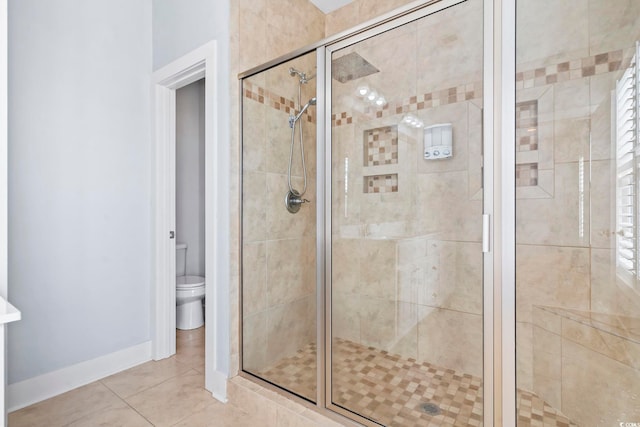 full bathroom featuring a stall shower, toilet, tile patterned flooring, and baseboards