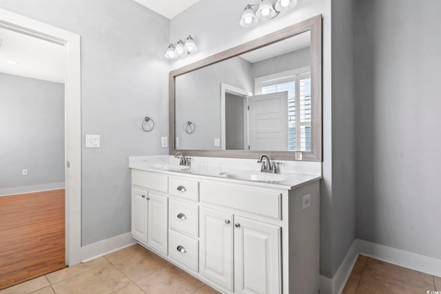 full bathroom with double vanity, baseboards, and tile patterned floors
