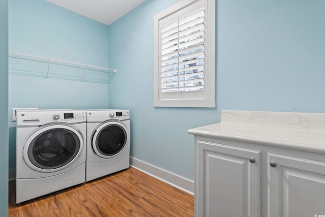 laundry room with washer and dryer, wood finished floors, cabinet space, and baseboards